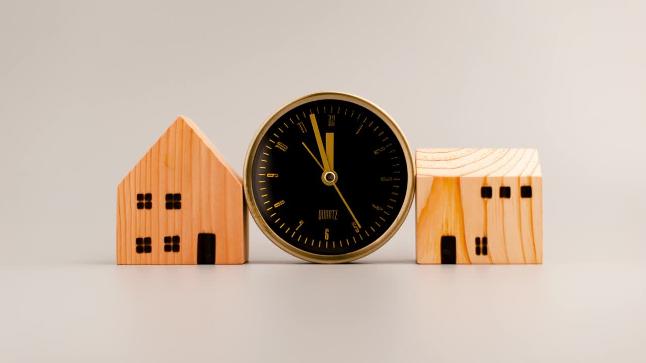 黄金闹钟以速度四处走动，木制房屋模拟住宅和房地产概念。视频素材