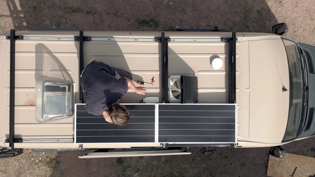 一名男子在一辆露营车的车顶上摆弄太阳能电池板视频下载