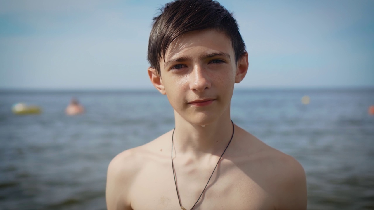 快乐的男孩在海滩上。年轻男子的脸在度假村的海洋之滨。严重的儿童肖像视频下载