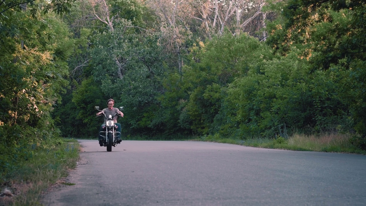 晚上，一个男人骑着摩托车经过森林小路视频素材
