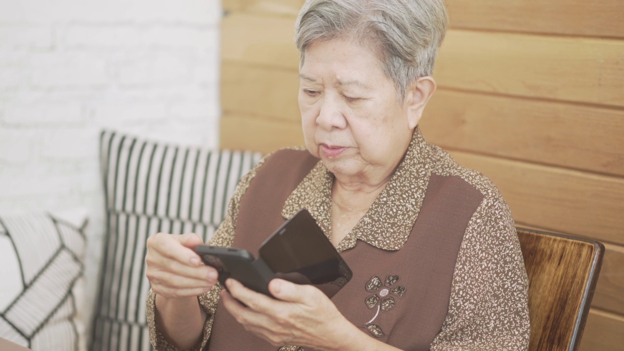 亚洲老人，老年，老年妇女，老年人使用手机上的社交媒体智能手机。成熟的退休描绘视频素材