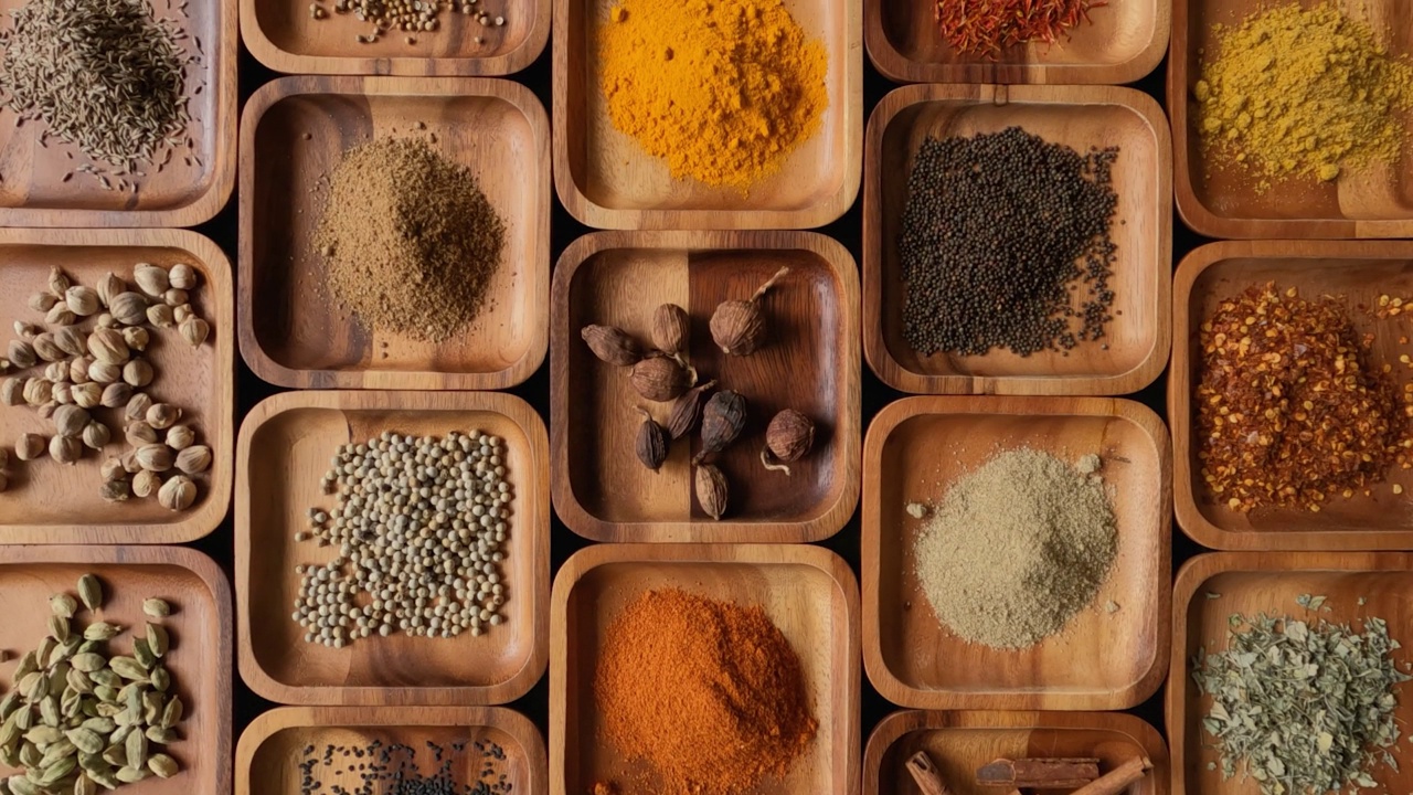 许多异国情调，充满活力的印度食物烹饪香料在方形木托盘展示。视频下载