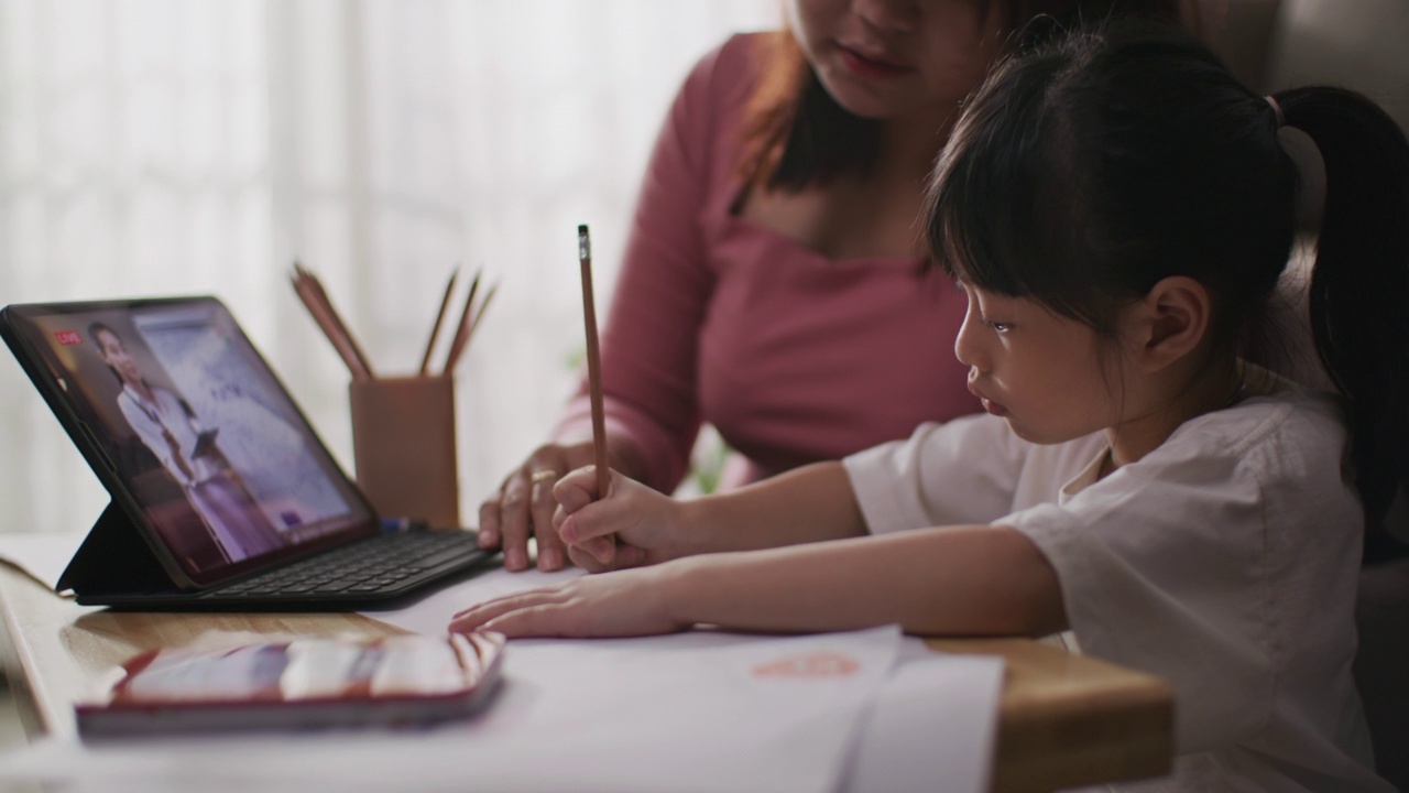 年轻的亚洲母亲和女儿在线课堂从学校老师通过数字远程互联网会议视频素材