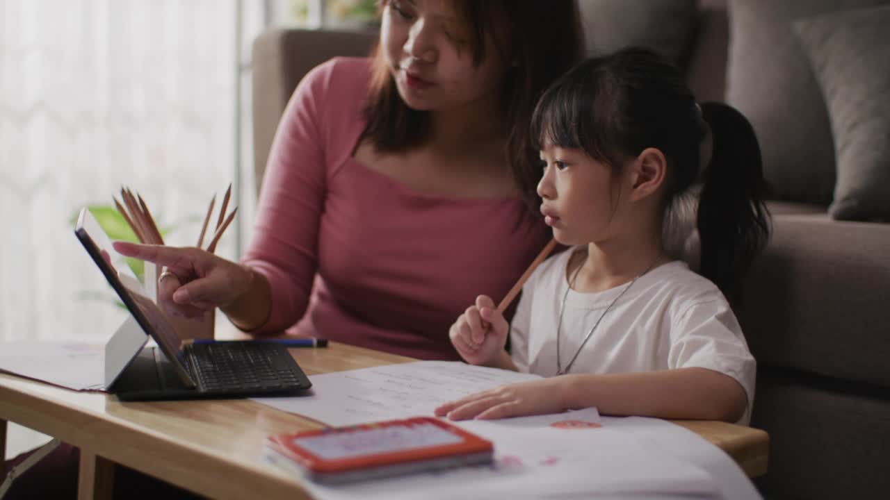 年轻的亚洲母亲和女儿在线课堂从学校老师通过数字远程互联网会议视频素材