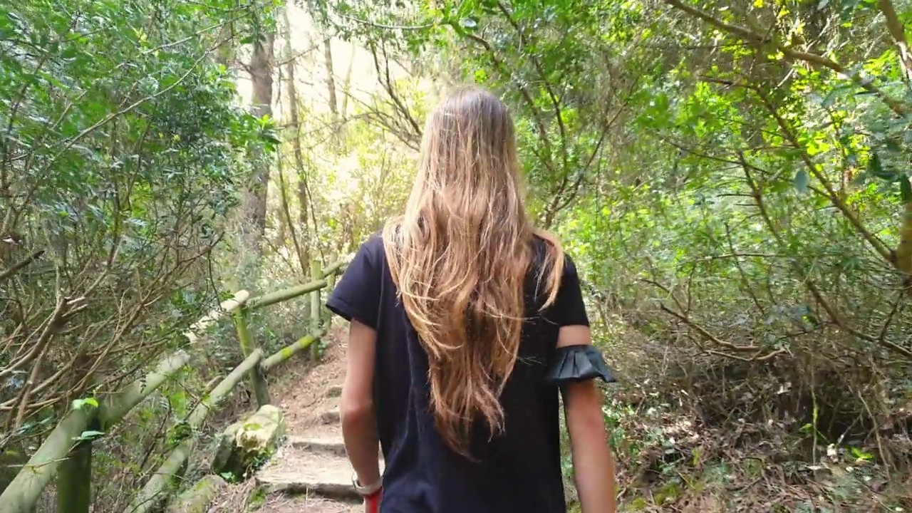 十几岁的女孩从后面看到爬石头楼梯和木制栏杆在自然视频素材