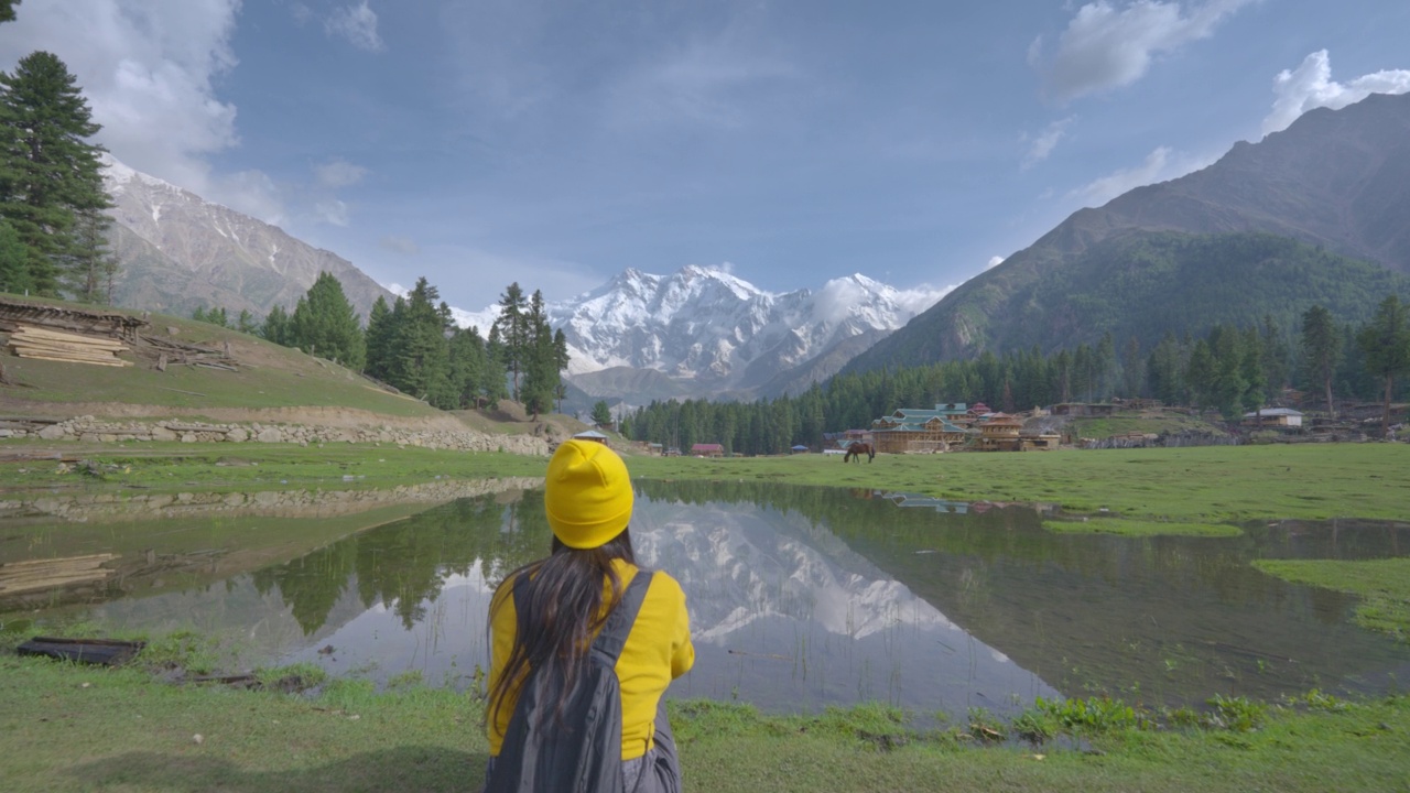 快乐的自由的旅行者年轻的女人穿着休闲的布黄色的帽子坐看山的倒影在山的水享受旅游假期。自然幸福的理念。视频素材