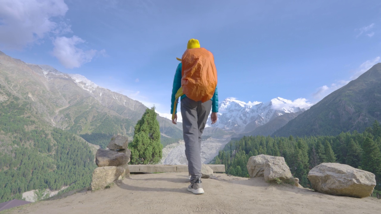 后视图，自由旅行者的快乐年轻的女性穿着冬季夹克蓝色的背背包在山顶上行走，享受旅游假期的山顶山顶。自然幸福的理念。与α香奈儿。视频下载