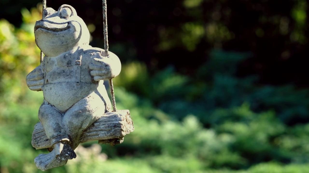 选择性对焦拍摄一只青蛙坐在秋千雕像上视频下载