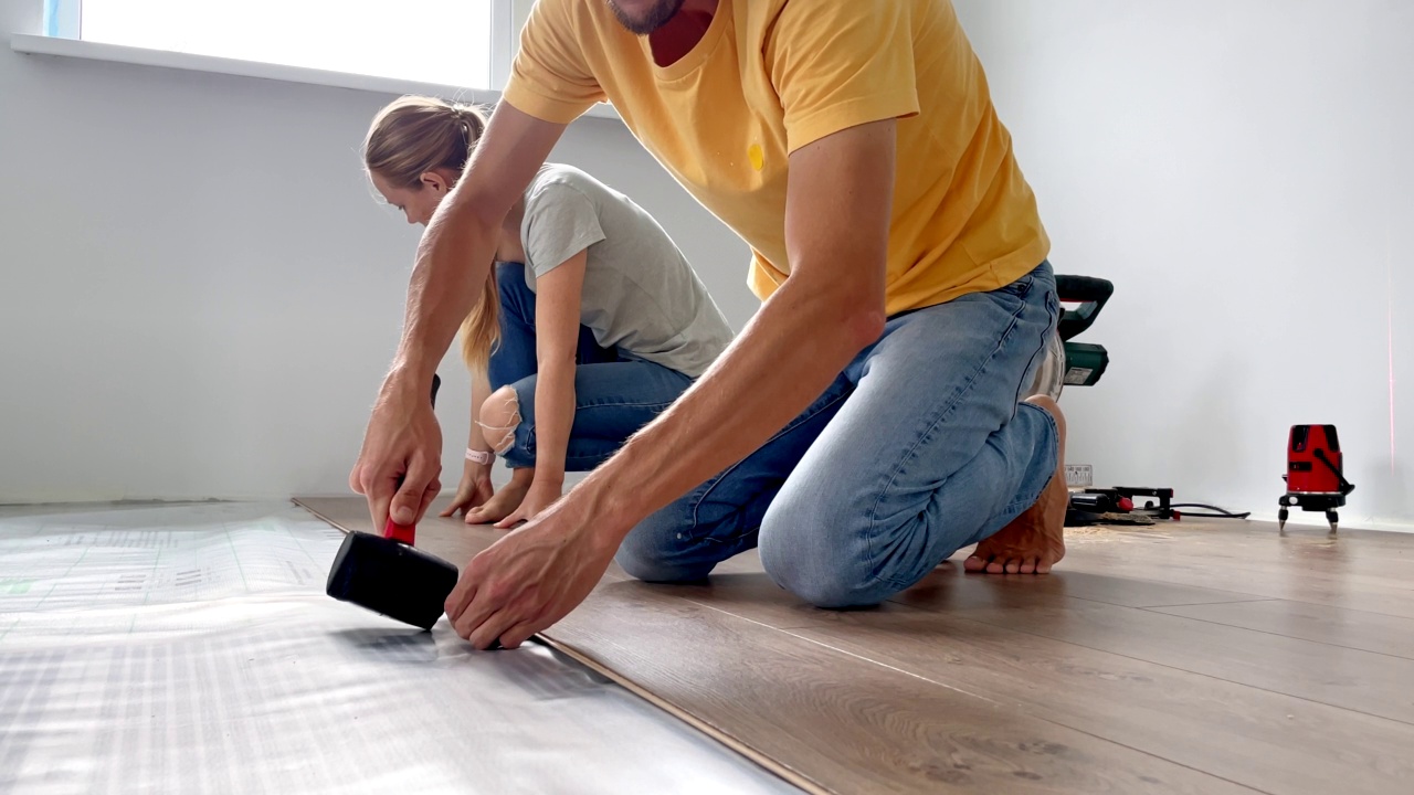 一个男人和一个女人在他们公寓的地板上安装层压板。DIY的概念。Slowmotion视频视频下载