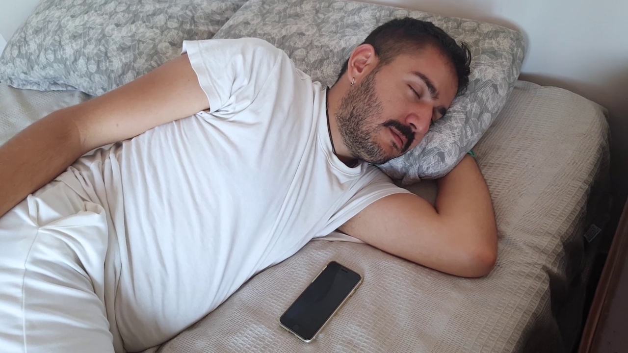 带着手机睡觉的男人视频素材