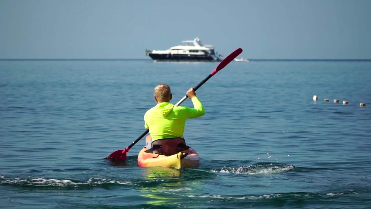 海人皮艇。运动员在夏天日落时划皮艇在海里游泳。健康强壮的男性喜欢在假期进行户外运动和水上运动。慢动作视频素材