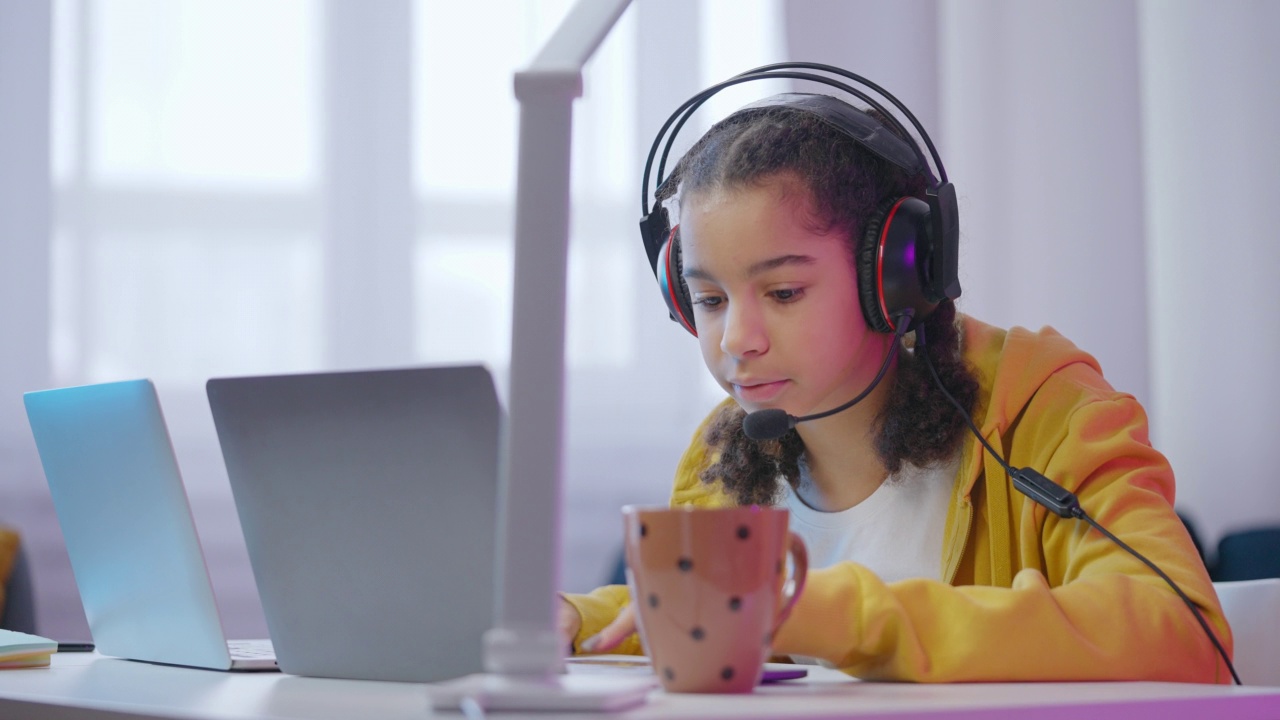 少女玩家戴着耳机在笔记本电脑上玩在线视频游戏，小玩意视频素材