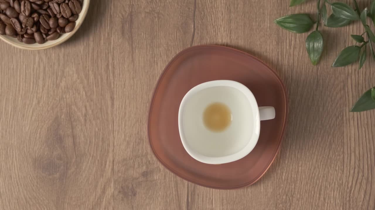 4k视频，平板咖啡白色杯在木制桌面。特浓咖啡热饮健康。在咖啡馆或家里的桌子上放一盆绿色植物。女手拿一杯热气腾腾的咖啡喝完而空杯视频素材