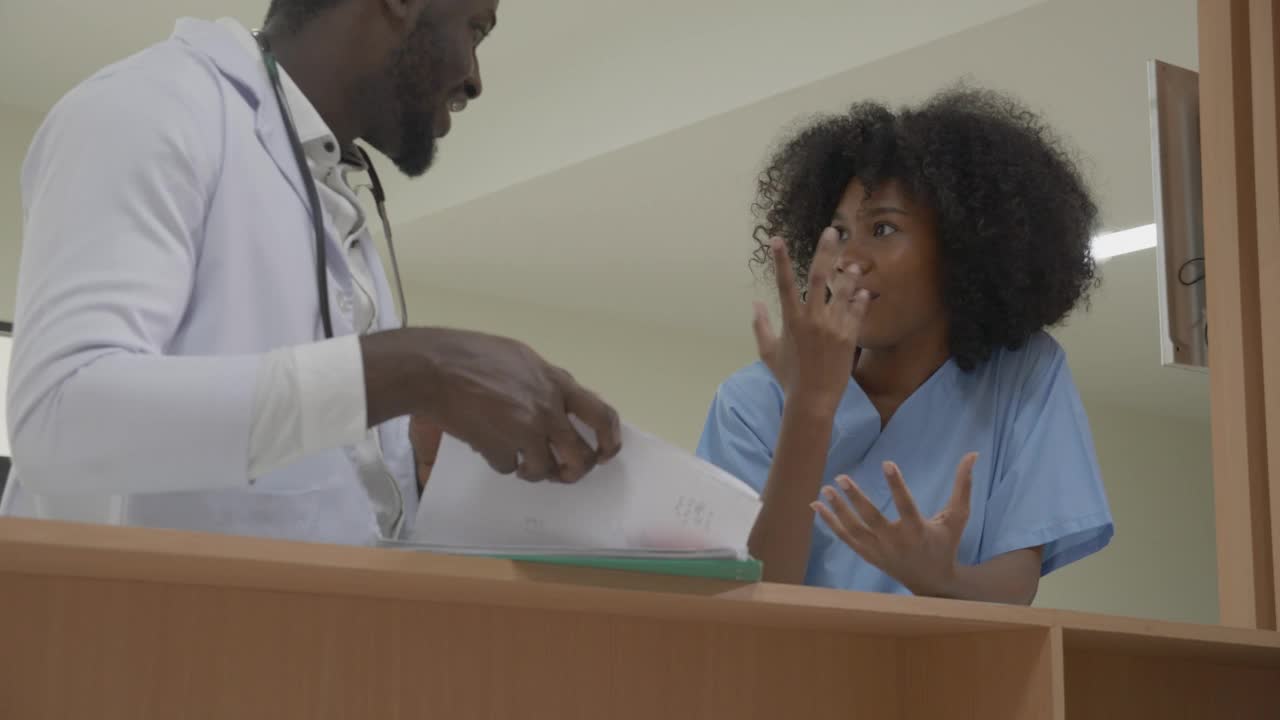 年轻的非洲裔美国医生专家在医院走廊与护士或助理诊断一起谈论和查看有关病人的文件，医疗和保险概念。视频素材