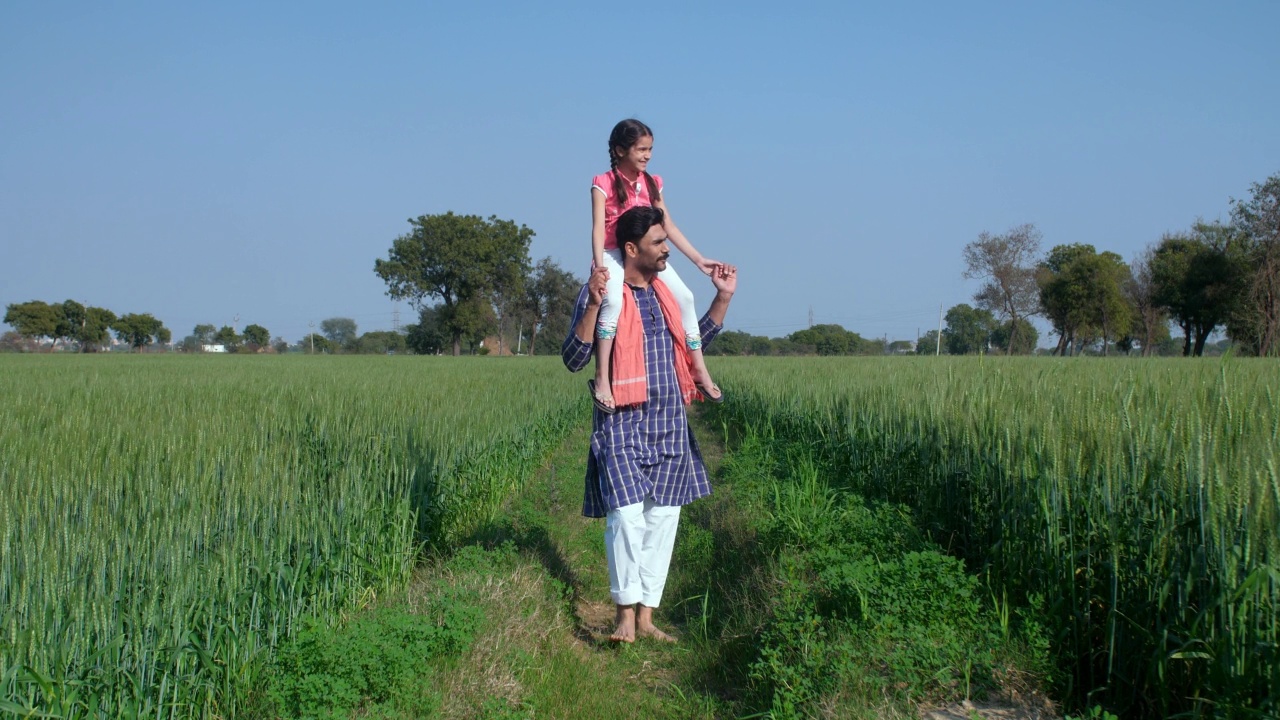 一对父女二人组喜欢在他们的绿色农田里漫步——印度村庄，绿色农田视频素材