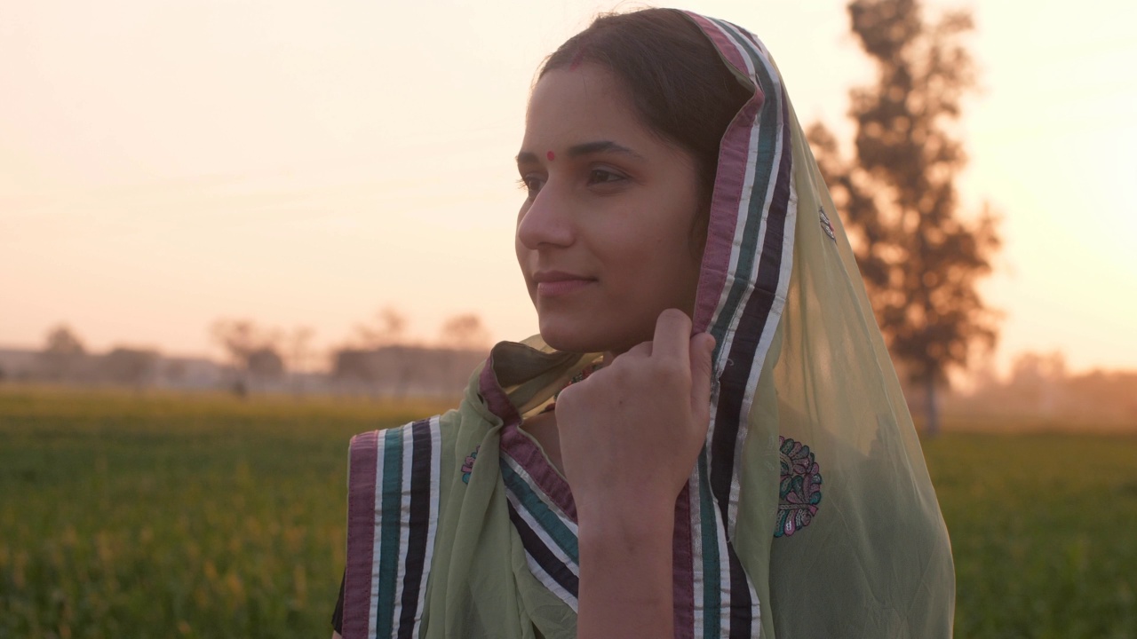 一个害羞的乡村女士/女农民的特写镜头站在她的农田-绿色的农田，印度农业视频素材