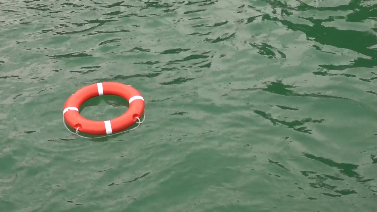 救生圈或救生带在绿水上闪耀着耀眼的阳光，在避暑胜地的泳池上，红色的救世主在泳池里视频下载