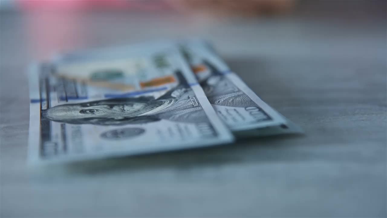女人在桌子上数100美元钞票。视频下载