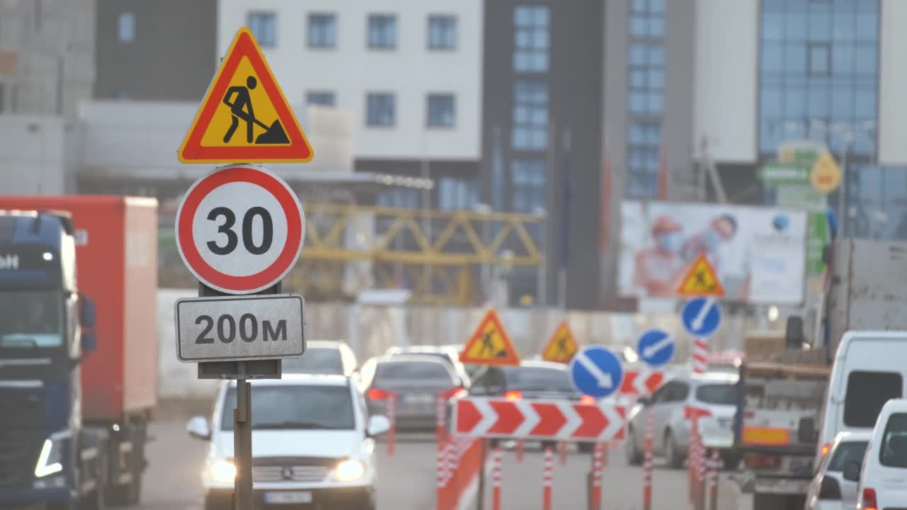 道路工程警告交通标志的建筑工程在城市街道和缓慢移动的汽车视频素材