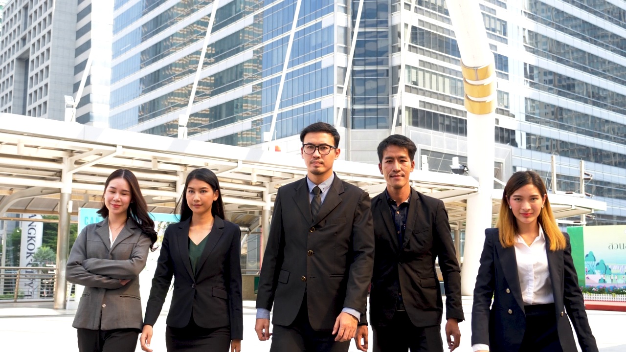 一群商务人士亚洲团队伙伴一起走在城市快乐。领导干部们以自信的团队精神站在现代都市都市。描绘多样性，商人和团队合作视频素材