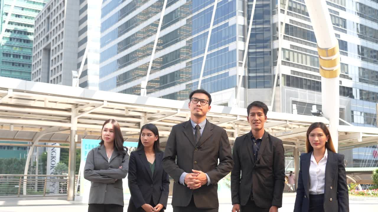 一群商务人士亚洲团队伙伴一起走在城市快乐。领导干部们以自信的团队精神站在现代都市都市。描绘多样性，商人和团队合作视频素材