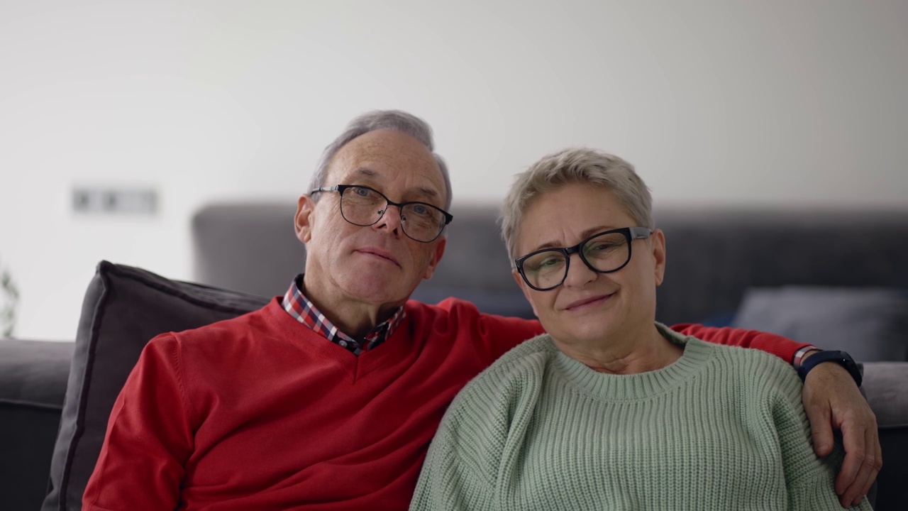 微笑的高加索老年夫妇拥抱和坐在沙发上的肖像视频下载