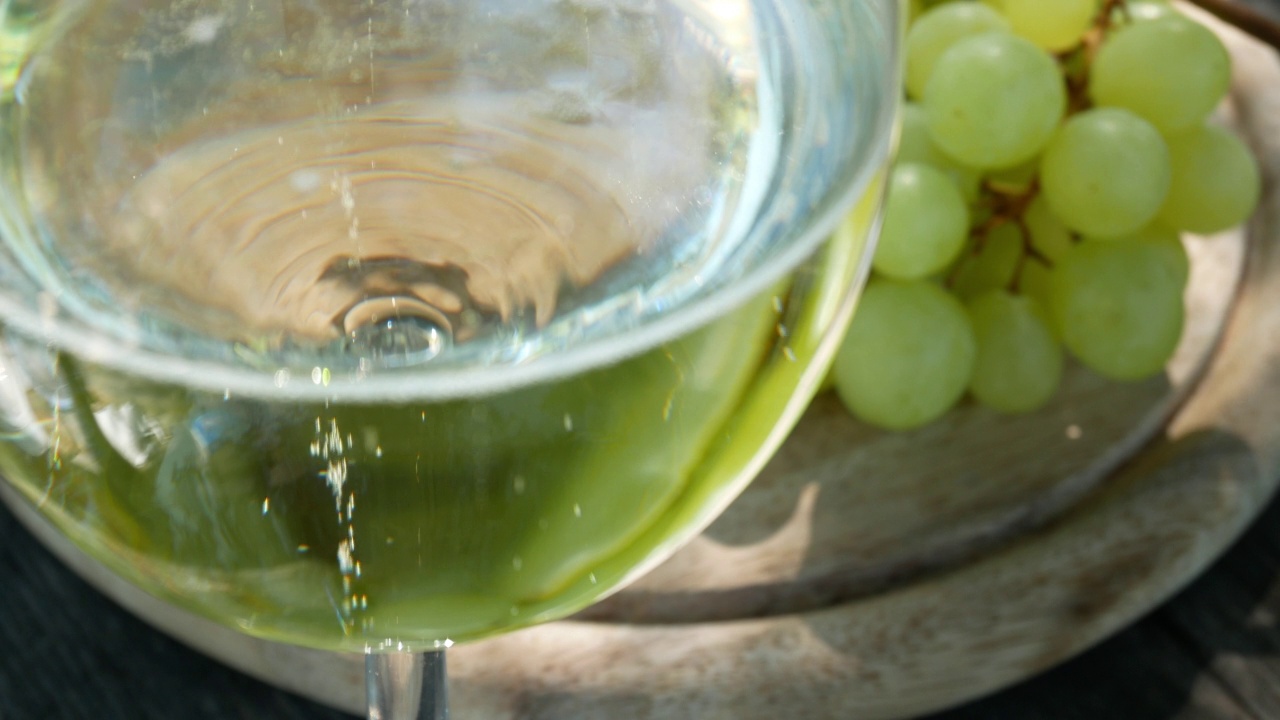 一杯气泡酒和葡萄在桌子上，意大利白葡萄酒视频视频下载