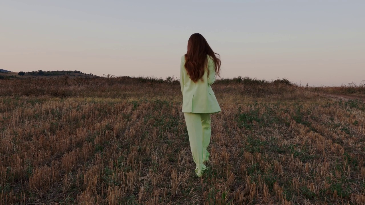年轻女子穿着薄荷绿西装在大自然中行走视频下载