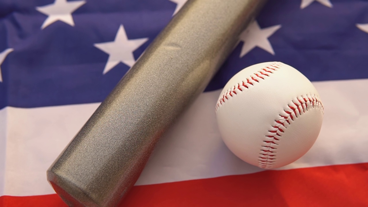 白色皮球和棒球棒放在美国国旗上，俯视图视频下载