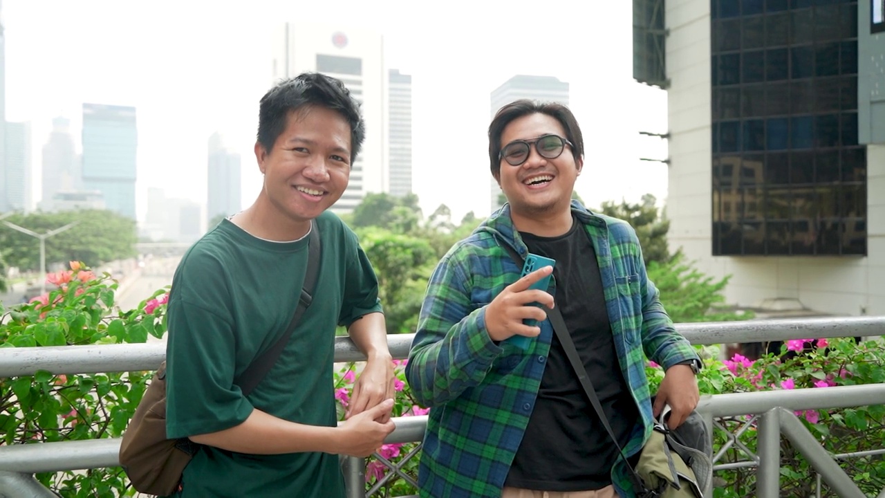 两名年轻的亚洲男子正在用手机观看雅加达的城市景观视频下载