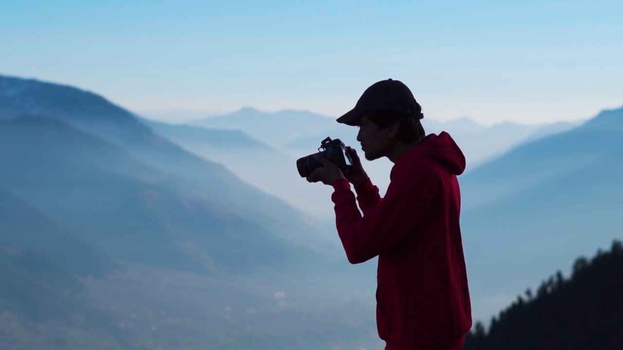 在喜马偕尔邦的马纳利，印度的一个印度摄影师在雾蒙蒙的喜马拉雅山脉前拍摄的剪影。旅行者拍山的照片。人拍摄的风景。视频素材