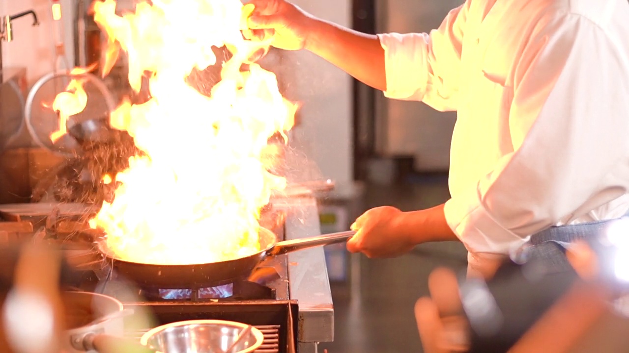 厨师拿着燃烧的平底锅，在厨房用燃烧的平底锅做饭视频素材
