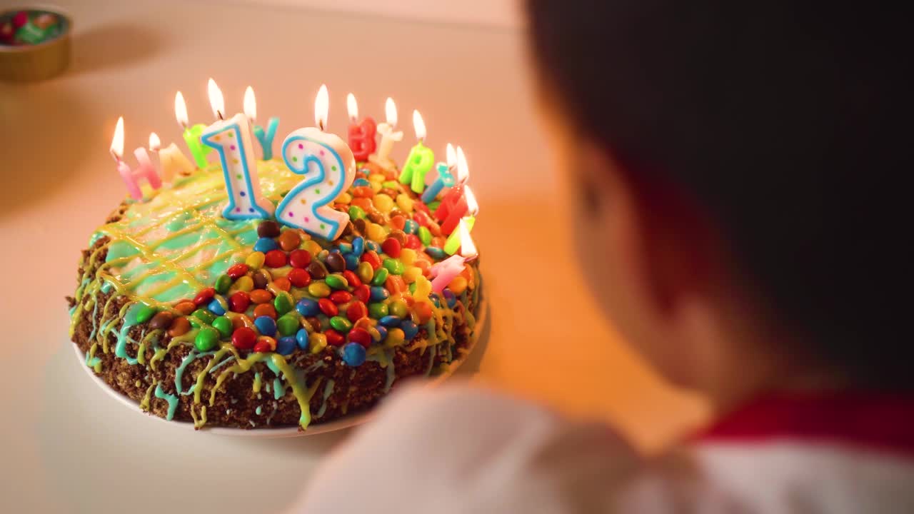 可爱的男孩吹灭了蛋糕上的蜡烛。少年在家里庆祝12岁生日视频下载