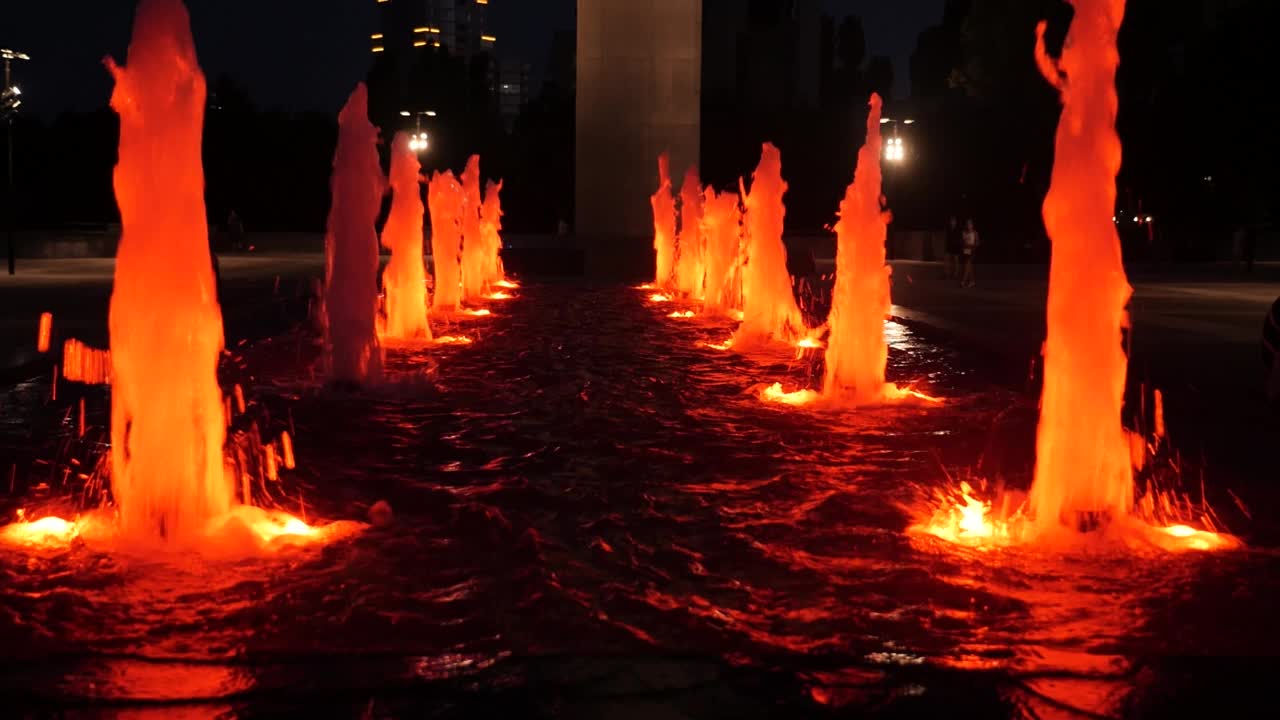 在城市的夜晚，五彩缤纷的喷泉和彩色的水花闪闪发光视频素材