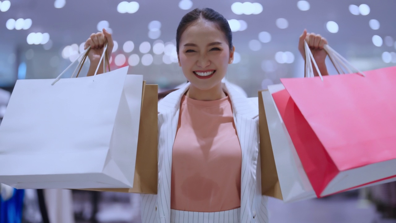 肖像美丽的亚洲女性女性女孩展示购物袋走退出愉快享受手势微笑购物在女性精品百货商场幸福的女人购物商场视频下载