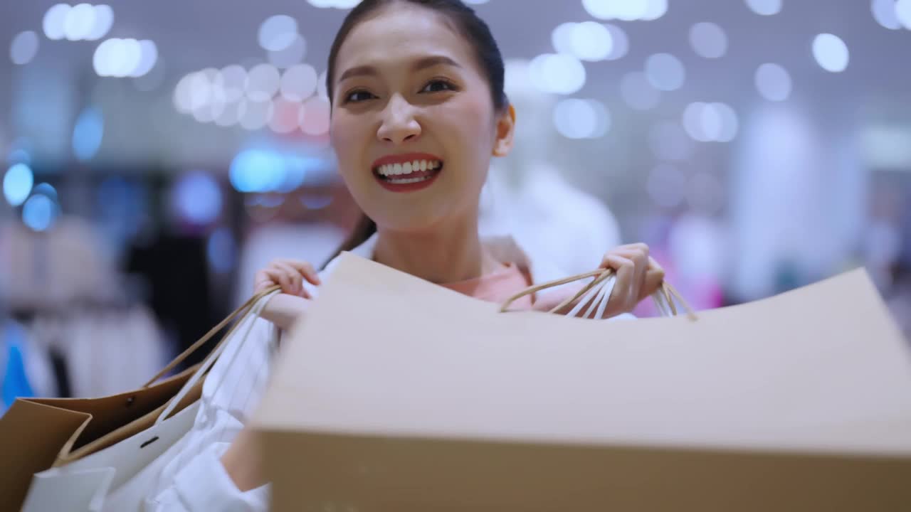 肖像美丽的亚洲女性女性女孩展示购物袋走退出愉快享受手势微笑购物在女性精品百货商场幸福的女人购物商场视频下载