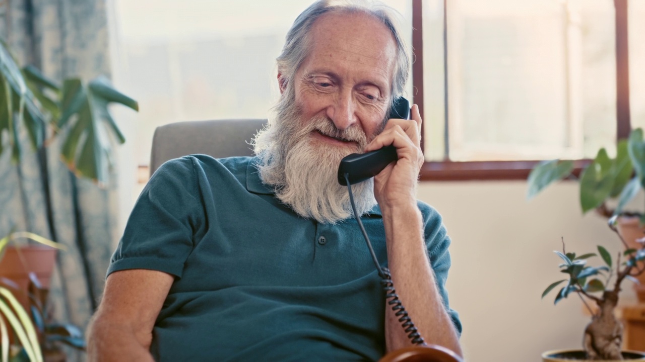 老人在有线老式电话上聊天，在家里愉快地享受退休生活。无忧无虑的成熟或年老的男性在家里放松，有一个有趣的电话交谈视频下载