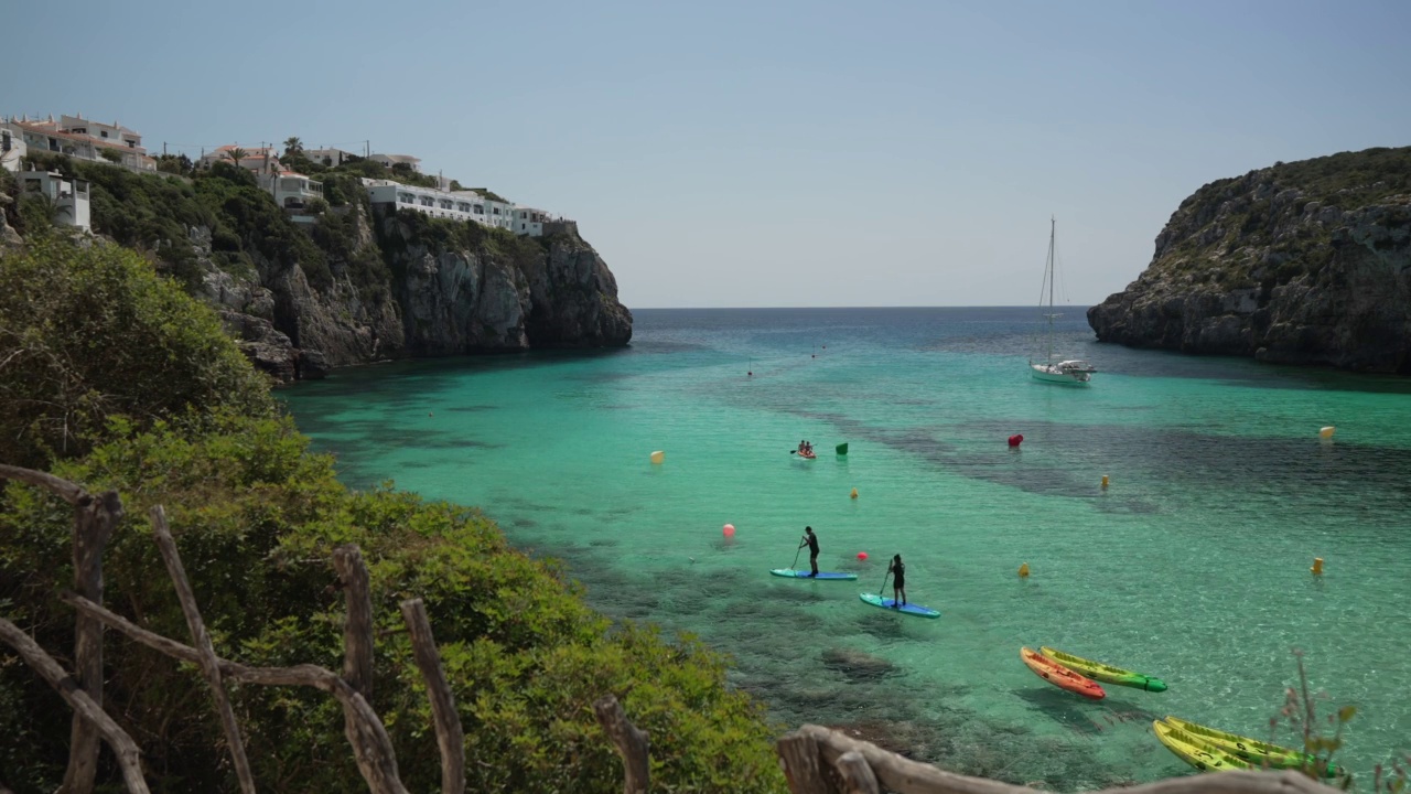 船在蓝绿色的水和水上运动俯瞰Cala en Porter, Menorca，巴利阿里群岛，西班牙，地中海，欧洲视频下载
