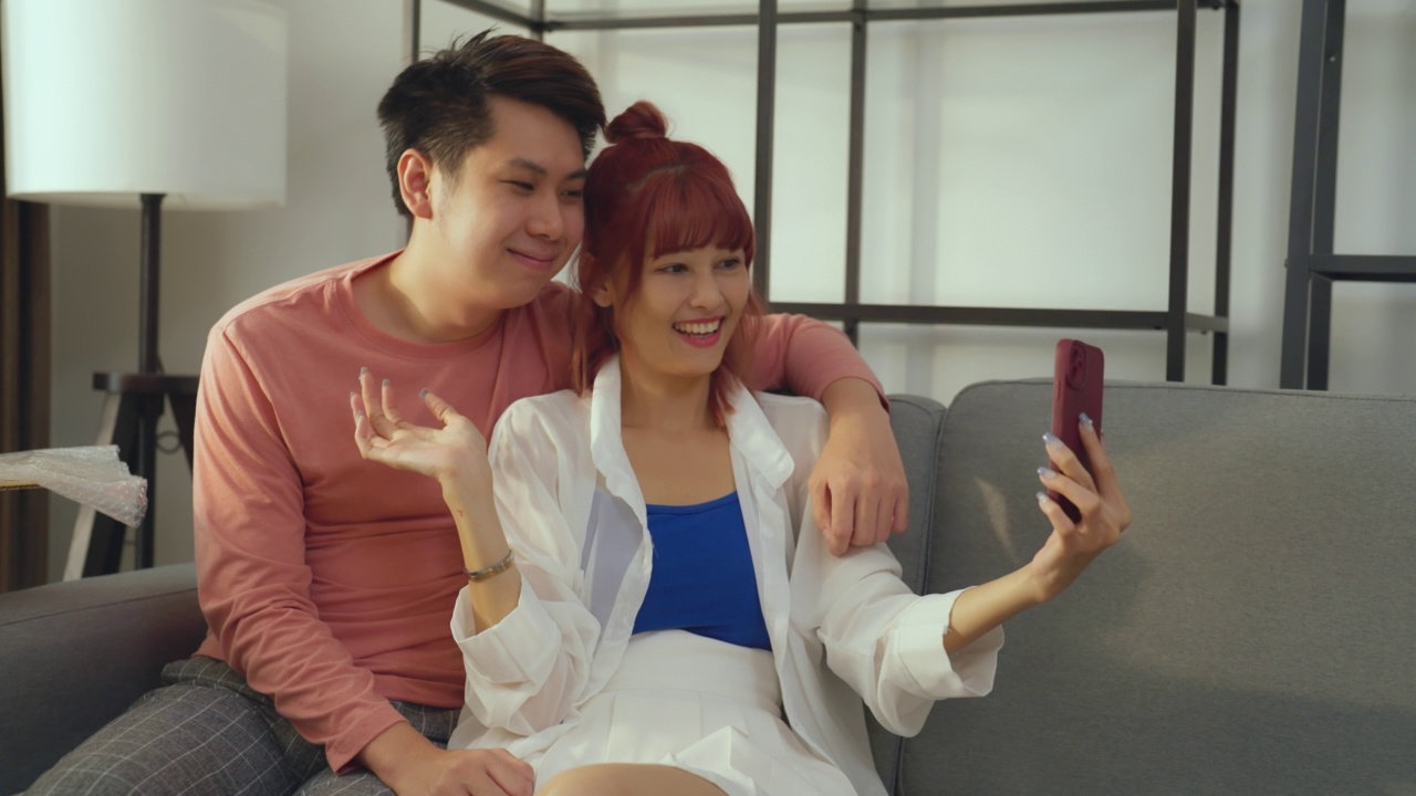 亚洲夫妇在客厅使用智能手机。视频素材