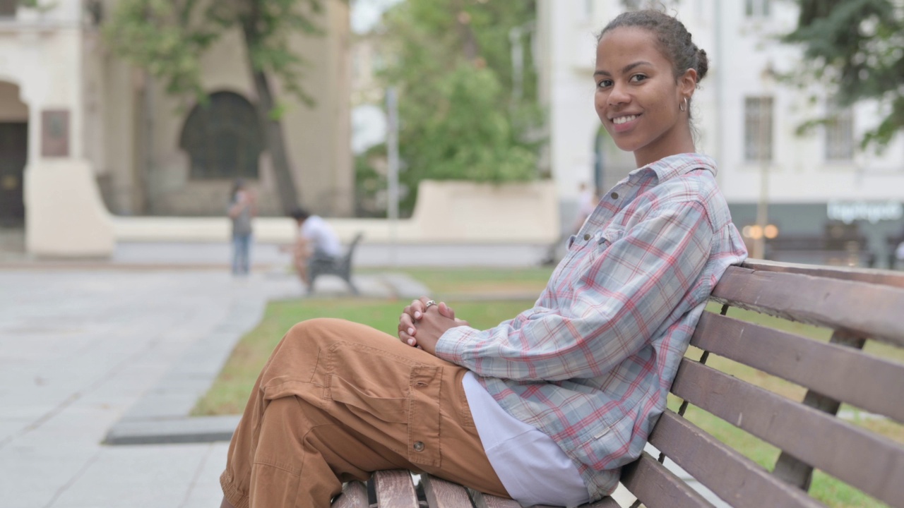 一名非洲妇女坐在长椅上对着镜头微笑视频素材