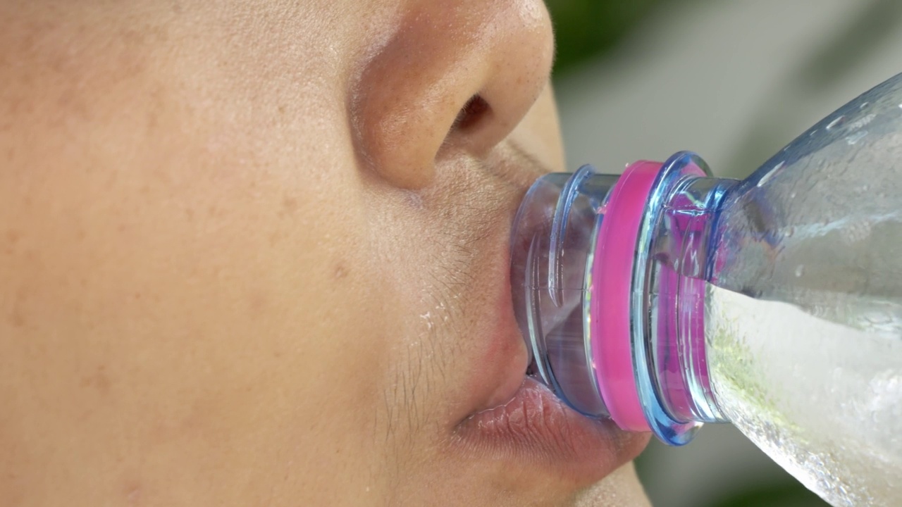 用瓶子喝水的亚洲女人。视频下载