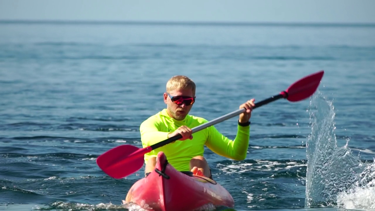 海人皮艇。运动员在夏天日落时划皮艇在海里游泳。健康强壮的男性喜欢在假期进行户外运动和水上运动。慢动作视频素材