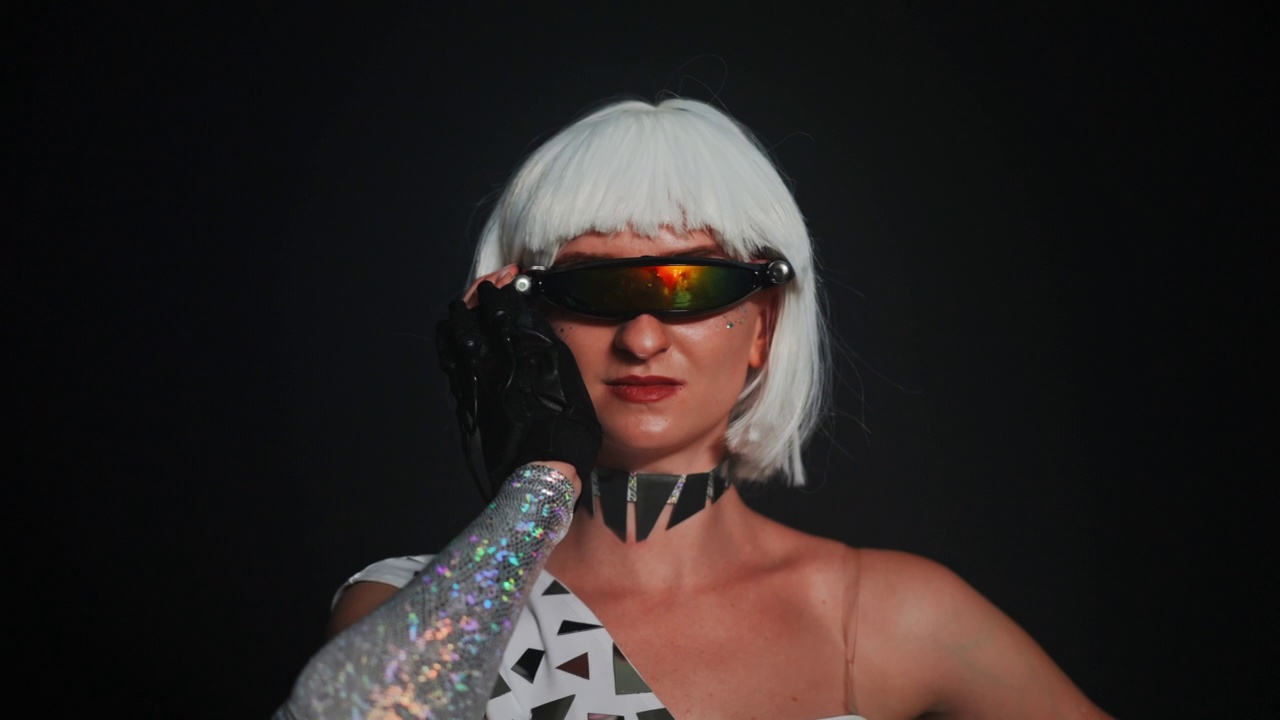 白种苗条的女人转向相机在慢动作打开红色霓虹灯的眼镜。自信的女性舞者在舞台上穿着未来主义服装表演的肖像。艺术的概念。视频下载