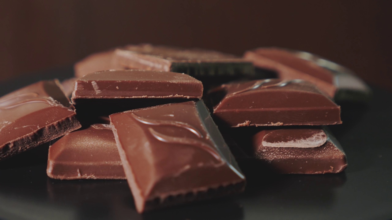 黑色背景上的巧克力棒顺时针旋转360度。视频素材