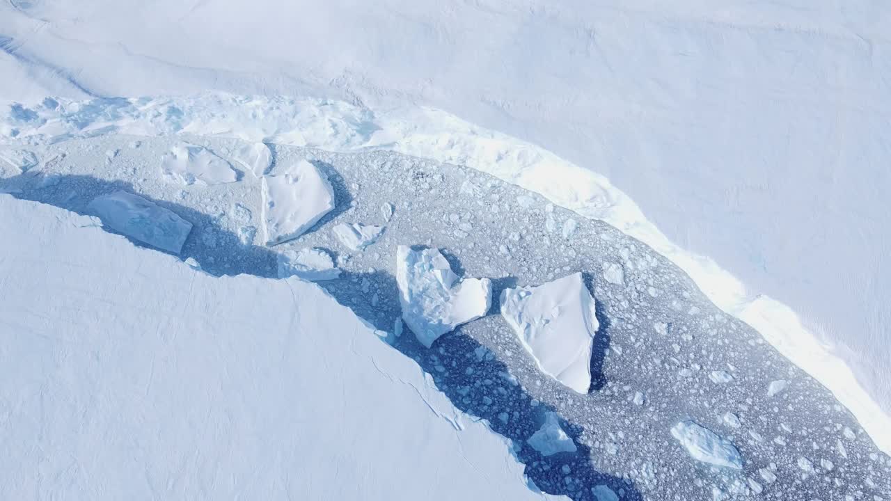 积雪覆盖的南极地面鸟瞰图飞行。视频下载