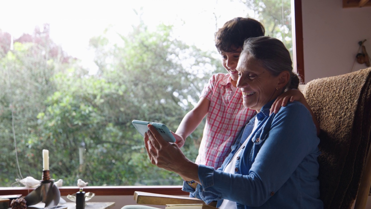 快乐的拉丁美洲奶奶在家用智能手机和孙子一起在线观看视频视频素材