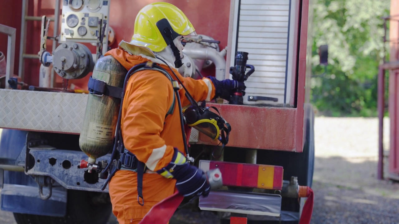 消防队员在工作前将洒水喷头连接到消防管线上，并待在事故发生区域的消防车后面视频下载