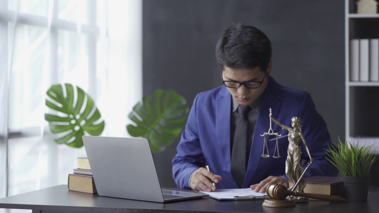 开始你的一天，在一个亚洲商业律师与法律服务的概念，在一个在线咨询办公室用笔记本电脑和锤子审判正义女神。视频下载