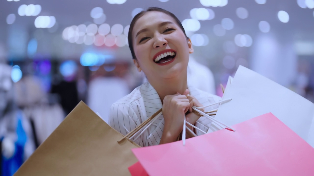 肖像美丽的亚洲女性女性女孩展示购物袋走出口愉快的享受手势微笑，而购物在女性精品百货商场幸福的女性购物中心视频下载