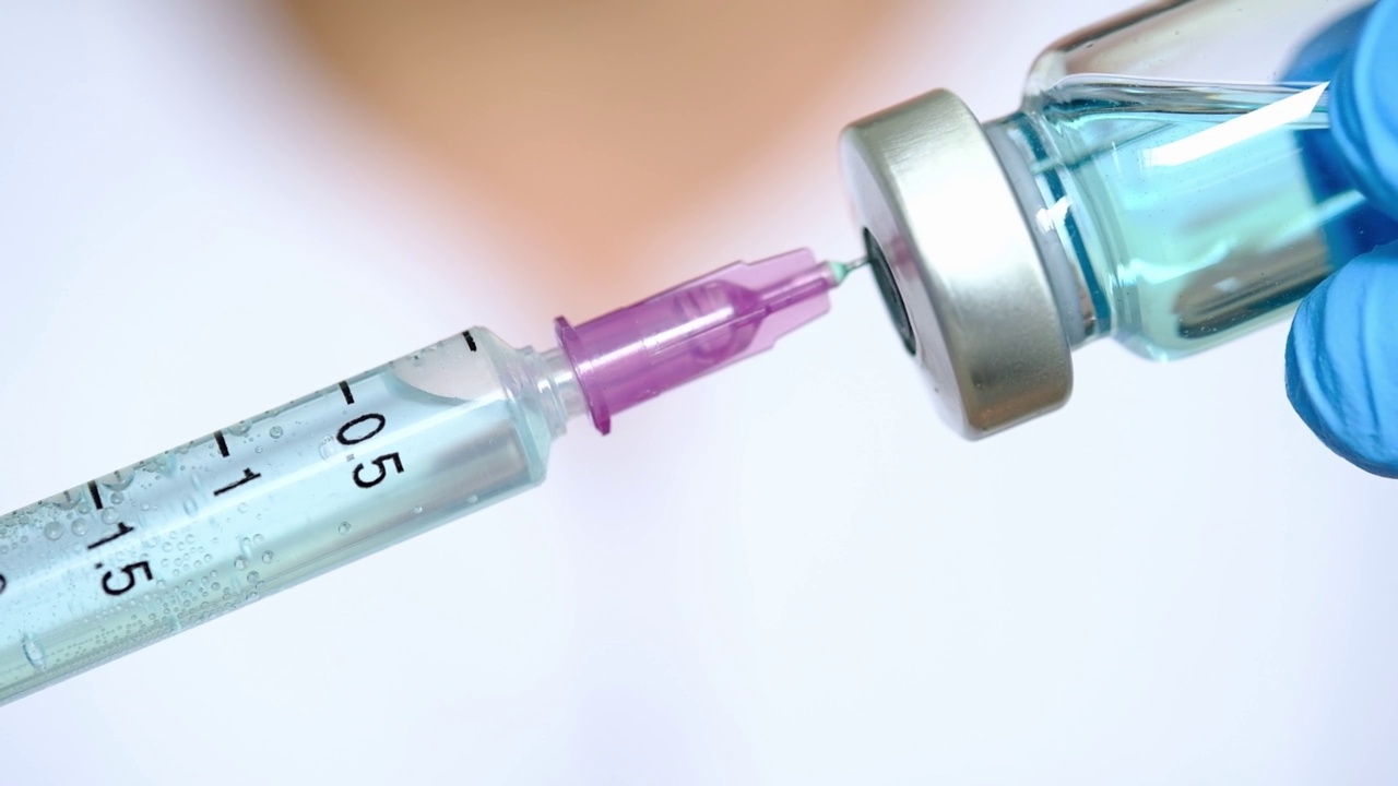 在医院里，医生的手拿着注射器和蓝色的疫苗瓶。健康和医学概念。视频素材